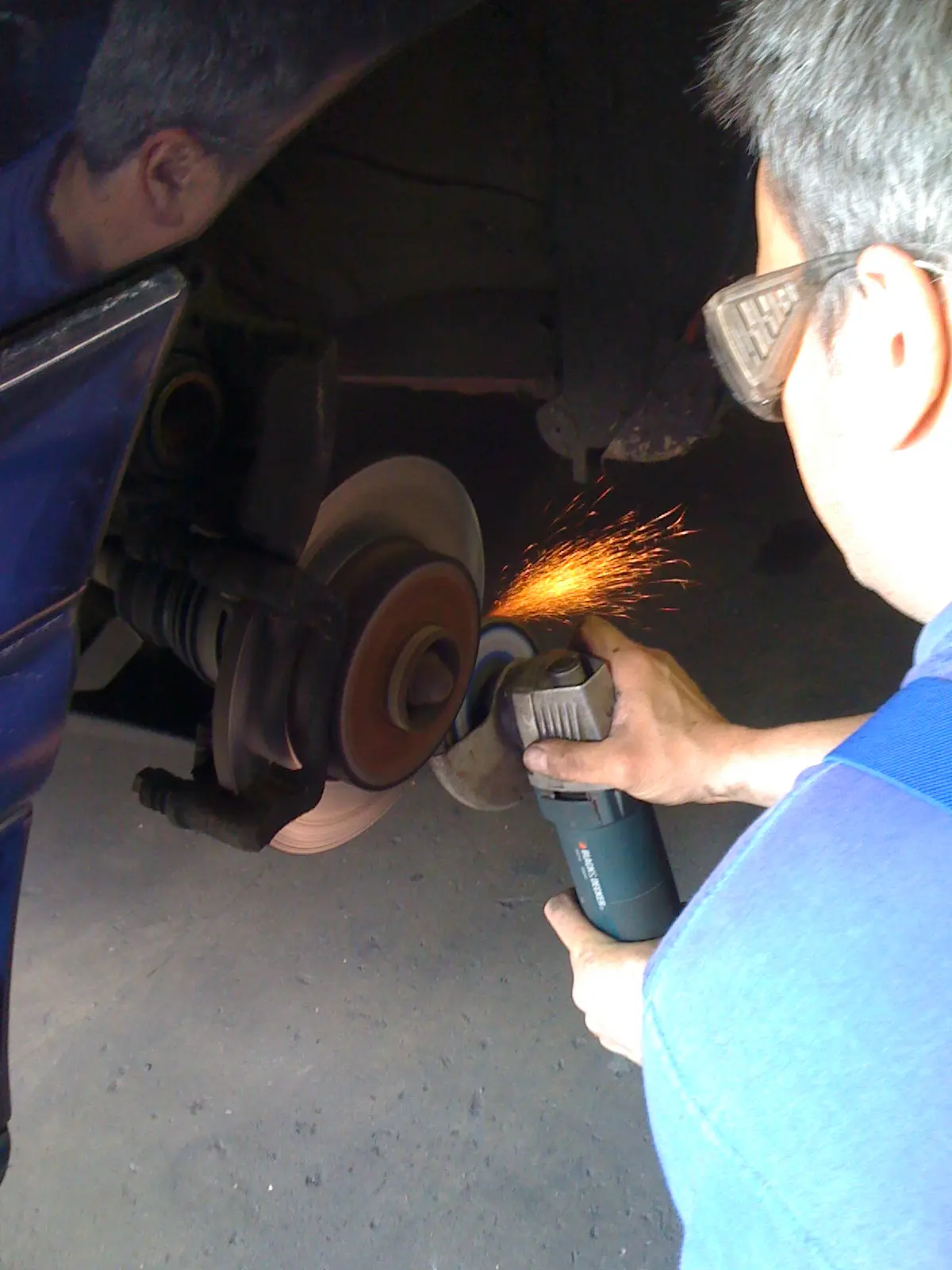 Sparks fly as a brake disc is ground on a workshop wheel