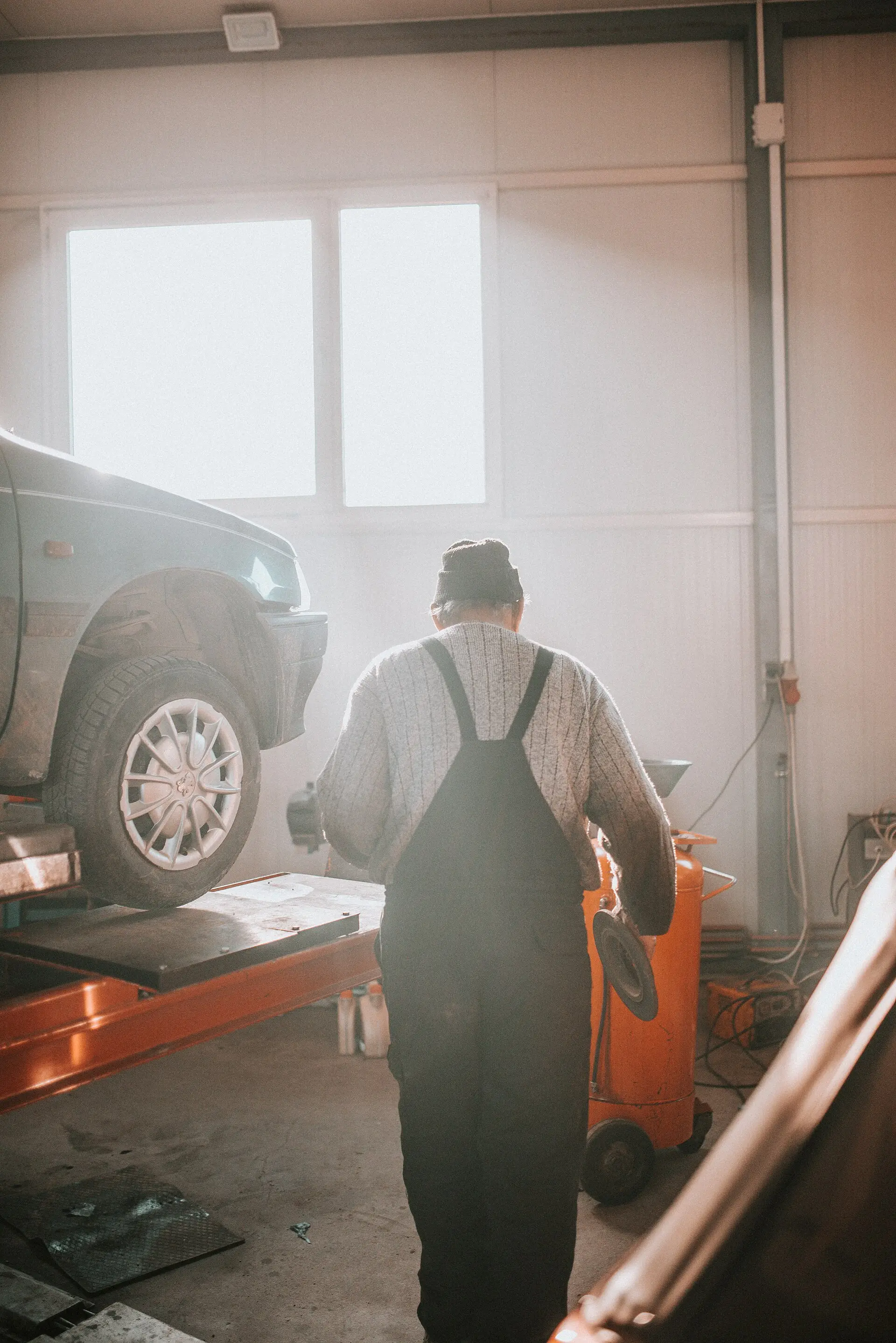 A mechanic works beneath a car raised on a lift in a repair garage